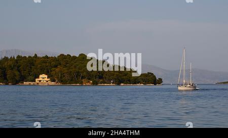 griechenland, griechische Inseln, ionische Inseln, lefkada oder lefkas, Bucht von nidri, Blick auf die vorgelagerte Insel in der Mitte, Festland im Hintergrund, Segelboot fährt von rechts nach links, Villa auf der Insel Stockfoto