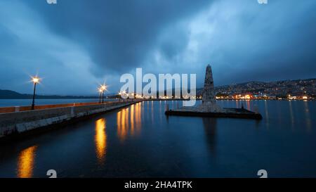 griechenland, griechische Inseln, ionische Inseln, kefalonia, argostoli, Hauptstadt von kefalonia, Abendaufnahme, Weitwinkelansicht, de bosset Brücke und Obelisk, Laternen werfen Lichtreflexe auf das Wasser, grau-blauer Himmel, bewölkt, argostoli beleuchtet im Hintergrund Stockfoto