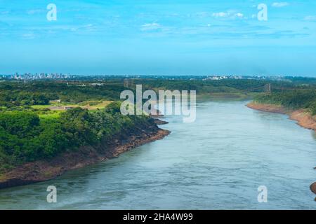 Parana Fluss an der Grenze von Brasilien und Paraguay mit einer entfernten Skyline Blick auf die paraguayische Stadt Ciudad del Este. Stockfoto