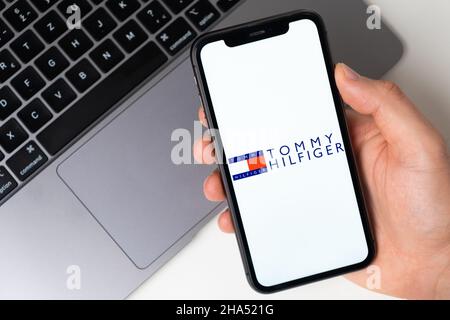 Tommy Hilfiger Anwendungslogo für Online-Shopping auf dem Bildschirm des Mobiltelefons. Mann Hand hält ein Smartphone mit Anwendung. November 2021, San Francisco, USA Stockfoto