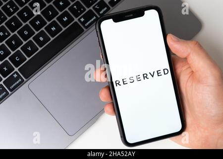 Reserviertes Logo der Anwendung für den Online-Einkauf auf dem Bildschirm des Mobiltelefons. Mann Hand hält ein Smartphone mit Anwendung. November 2021, San Francisco, USA Stockfoto