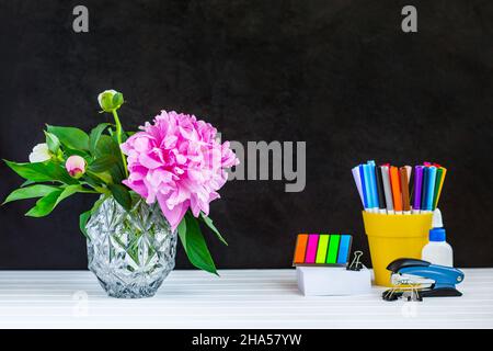 Lehrer oder Schüler Schreibtisch Tisch. Bildung Hintergrund. Bildung mockup Konzept. Zerstreut, Buntstifte, leeres Papier Seite, gestapelte Bücher, grüne Pflanze Stockfoto