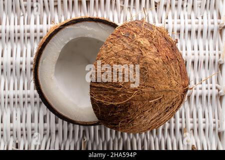 Zwei Hälften frischer Kokosnuss, Nahaufnahme, auf einer Weinmatte, Draufsicht. Stockfoto