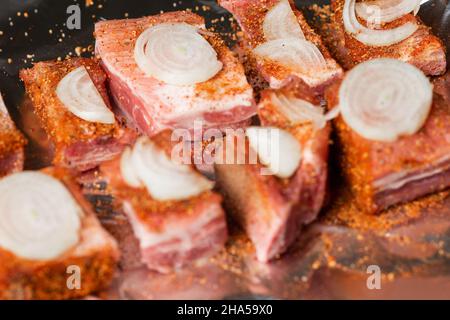 Rohe Schweineribs mit rohen Zwiebeln liegen auf Folie, fertig zum Backen im Ofen. Stockfoto