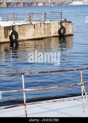 Winteransicht der verlassenen Flusspiers am Dnjepr. Rostige Poller im Schnee. Die Piers sind mit Schnee bedeckt. Stockfoto