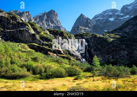 Idyllischer kleiner Wasserfall vor wilden Felsbergen oberhalb des erstfeldertals an einem sonnigen Sommertag. uri alpen,schweiz,europa. Stockfoto