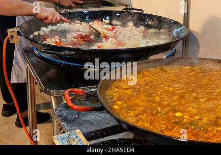 Kochvorgang einer traditionellen valencianischen Paella in einer Paella-Pfanne mit einem Gasfeuer. Stockfoto