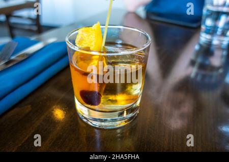 Altmodisches Whiskey-Getränk in einem Cocktailglas mit Eis auf einem Holztisch in einer Restaurantbar Stockfoto
