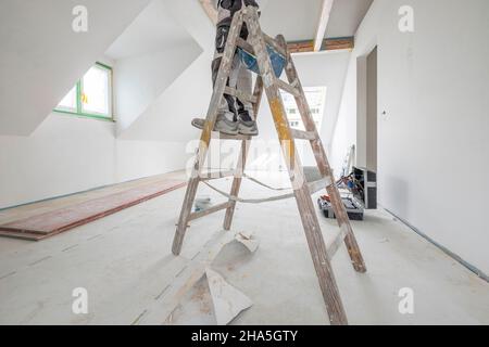 Baustelle, Sanierung und Renovierung einer Wohnung, Maler auf einer Leiter im Dachgeschoss Stockfoto