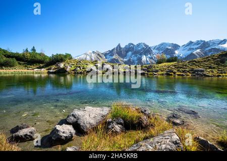 Kleiner Bergsee vor verschneiten Felsbergen an einem sonnigen Herbsttag bei oberstdorf. Guggersee, allgäuer alpen, bayern, deutschland, europa Stockfoto