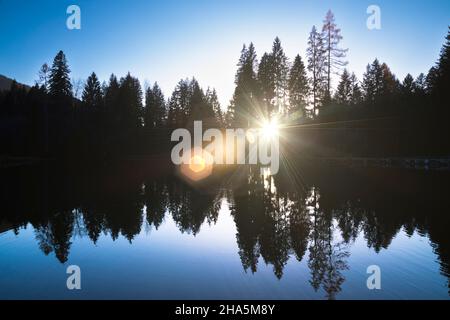 Bäume und Reflexionen im See der Villa welsperg, Hintergrundbeleuchtung mit Lichtreflexen,val canali,primiero san martino di castrozza,trient,trentino Alto adige,italien Stockfoto