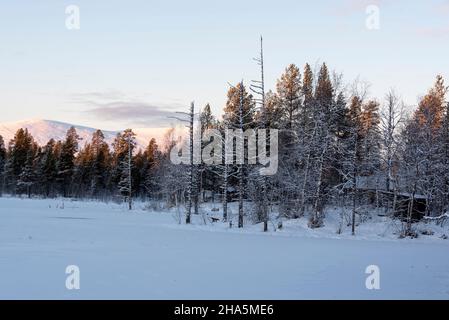 Hütten im Wald, schneebedeckter See, hinter dem pallastunturi, yli-kyrön, lappland, finnland Stockfoto