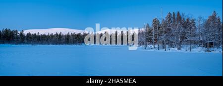 Hütten im Wald, schneebedeckter See, hinter dem pallastunturi-Gebirge, yli-kyrön, lappland, finnland Stockfoto