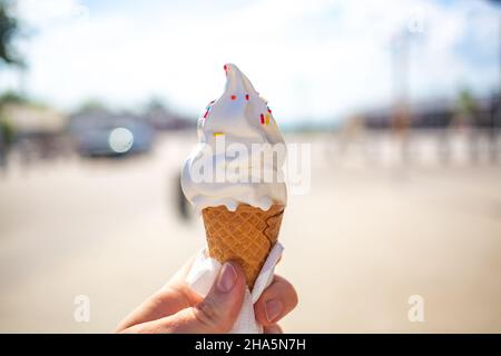 Girl'S Hand hält Eis im Waffelkegel dekoriert mit Pillen an einem heißen Tag draußen Stockfoto