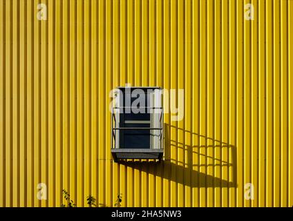 Bunte Industriearchitektur, gelbe Fassade, Tür mit Schatten, Stockfoto