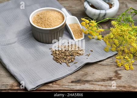 Arbeitsschritte mit Fenchelsamen und Fenchelsamen zur Herstellung von Fenchelsaft, den Zutaten Rohrzucker, Fenchelsamen und Fenchelsamen auf einem Holztisch Stockfoto