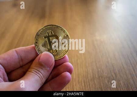 Die Hand des Mannes hält eine goldene Bitcoin-Münze. Foto des Investitionskonzepts für Kryptowährungen. Stockfoto