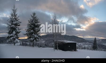 Schwarze moderne kleine Hütte auf verschneiten Karpaten in der Ukraine Stockfoto