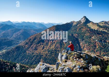 Wanderer auf dem leonhardstein genießen an einem sonnigen Herbsttag den Blick über die bayerischen voralpen. Berge, Hügel und Wälder unter blauem Himmel. mangfallberge, bayern, deutschland, europa Stockfoto