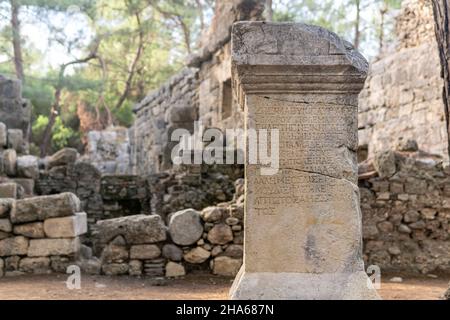 Phaselis, Türkei - 08. November 2021: Halbgelöschte antike griechische Inschrift auf einem Stein unter den Ruinen der antiken Stadt Stockfoto