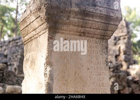 Phaselis, Türkei - 08. November 2021: Halbgelöschte antike griechische Inschrift auf einem Stein unter den Ruinen der antiken Stadt Stockfoto