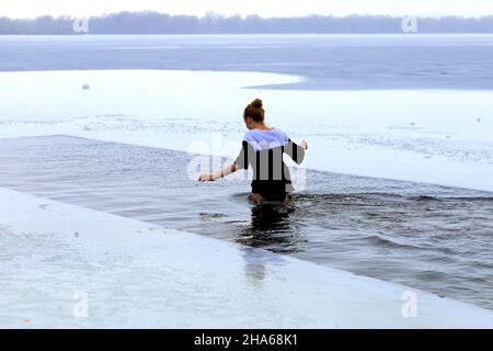 Schwimmen im Winter. Aushärtung. Während des orthodoxen Epiphanie-Festes schwimmt eine Frau in einem wintereisbedeckten Fluss. Dnipro, Dnipropetrowsk, Ukraine Stockfoto