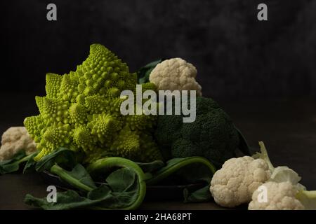Romanesco-Kohl, Brokkoli und Blumenkohl aus der Nähe auf dunklem Hintergrund Stockfoto