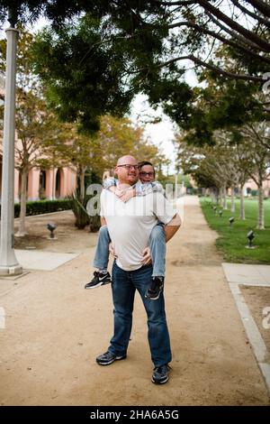 Vater gibt zehn Jahre alten Sohn eine Huckepack Fahrt in San Diego Stockfoto