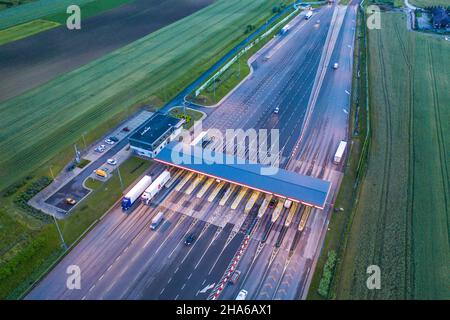 Autotransport auf mehrspurigen Autobahn Straße und Mautentor, Drohne Antenne Draufsicht in der Nacht. Pendlerverkehr, City Life Konz Stockfoto