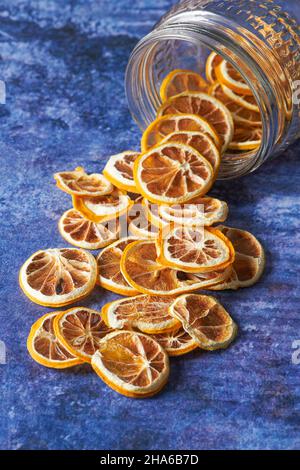 Getrocknete Orangenscheiben, die aus einem Glas in das Innere fallen. Trockenobstkonzept Stockfoto