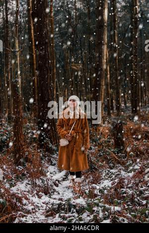 Frau, die einen verschneiten Wald im Nordwesten Englands erkundet. Delamere Forest ist ein großer Wald im Dorf Delamere in der englischen Stadt Ceshire Stockfoto