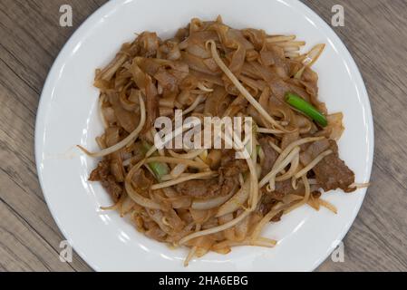 Die Ansicht von oben über die Rinderkau-Mein-Nudeln macht einen riesigen Haufen auf dem Teller für ein köstliches chinesisches Essenserlebnis. Stockfoto