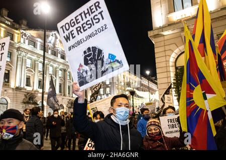 Ein Protestler hält ein Plakat mit der Aufschrift „gemeinsam widerstehen wir. Keine Peking 2022' während des Protestes. Zur Feier des Menschenrechtstages (10th. Dezember) versammelten sich verschiedene Gruppen gegen die Kommunistische Partei Chinas (gegen die KPCh) in London am Piccadilly Circus und marschierten später zur Downing Street 10. Nach einer gewalttätigen Schlägerei in Chinatown am 27th. November, bei der Hong Kongers verletzt wurden. Hongkong, Tibeter und Uiguren kamen zusammen, um die Versuche der KPCh aufzudecken, abweichende Stimmen zu unterdrücken. Die Kundgebung forderte die westliche Welt majorly auf, die Olympischen Winterspiele 2022 in Peking zu boykottieren. (Foto von Belinda Jia Stockfoto
