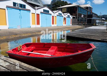 Red Dingy vor Blue Boat Sheds, Boat Harbour, Wellington, North Island, Neuseeland Stockfoto