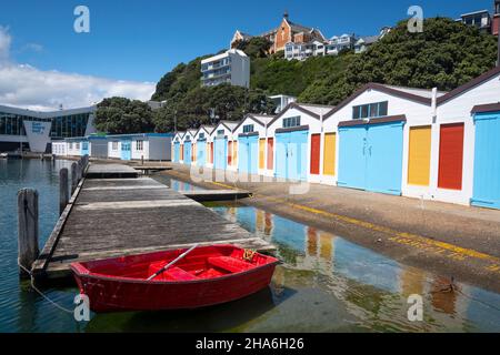 Red Dingy vor Blue Boat Sheds, Boat Harbour, Wellington, North Island, Neuseeland Stockfoto