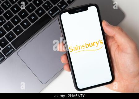 Sainsburys die Anwendung ist im Smartphone geöffnet. Der Mann hält ein Mobiltelefon in der Hand, die Unternehmensanwendung ist auf dem Bildschirm geöffnet. Sicheres Online-Shopping. November 2021, San Francisco, USA Stockfoto