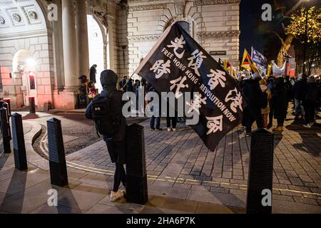 London, Großbritannien. 10th Dez 2021. London, Großbritannien. 10th Dez 2021. Während einer Kundgebung in London winkt ein Protestler mit der Aufschrift „Free Hong Kong, Revolution Now“. Verschiedene Gemeinden gegen die Kommunistische Partei Chinas (gegen die KPCh) in London versammelten sich am Piccadilly Circus und marschierten später zur Downing Street 10. Hongkong, Tibeter und Uiguren kamen zusammen, um die Versuche der KPCh zu verurteilen, abweichende Stimmen zu unterdrücken. Die Demonstranten forderten auch die westliche Welt auf, die Olympischen Winterspiele 2022 in Peking als Reaktion auf die Unterdrückung der Menschenrechte in China zu boykottieren. Stockfoto