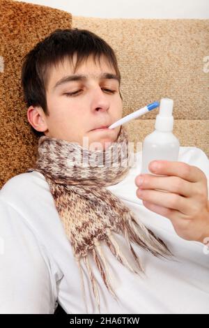 Kranker Teenager mit Thermometer und Droge auf dem Sofa zu Hause Stockfoto