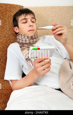 Kranker Teenager mit Thermometer und Droge auf dem Sofa zu Hause Stockfoto