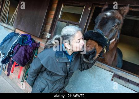Eine reife Reiterin verbringt die letzten kostbaren Stunden, bevor ein Pferd aufgrund von schlechtem Gesundheitszustand und Alter abgesetzt wird. Stockfoto