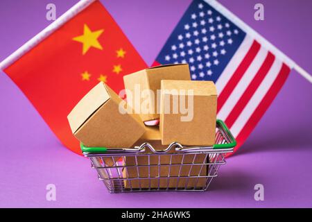 Verschiedene Boxen in einem Lebensmittelkorb und Flaggen von China und Amerika auf einem farbigen Hintergrund, das Konzept des Handels zwischen Ländern Stockfoto