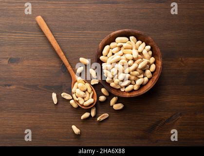 Erdnüsse in einer Holzschale auf einem Holztisch. Stockfoto