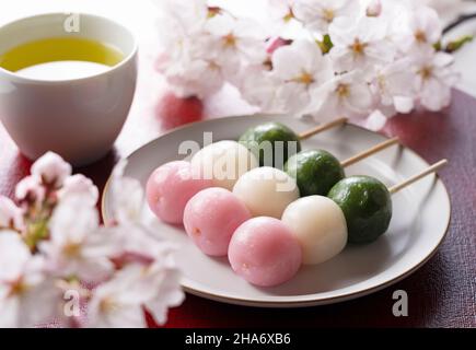 Dreifarbige Knödel auf einem roten Tablett. Bild des japanischen Frühlings. Stockfoto