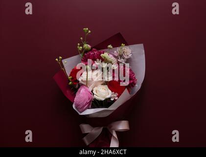 Ein Blumenstrauß vor einem dunkelroten Hintergrund. Von direkt oben betrachtet. Stockfoto