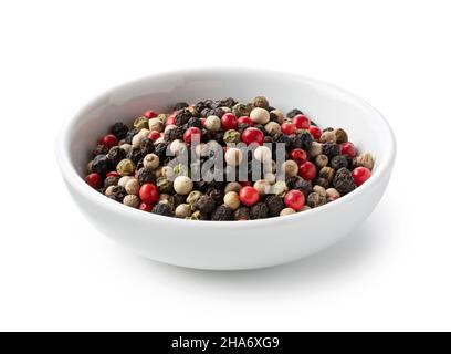 Pfeffer in einem Teller mischen. Schwarze, rote, weiße und grüne Pfefferkörner auf weißem Hintergrund Stockfoto