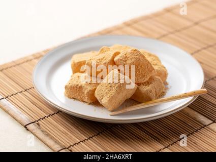 Warabi Mochi platziert auf einem japanischen Platzdeckchen. Warabimochi ist eine traditionelle japanische Süßigkeit. Stockfoto