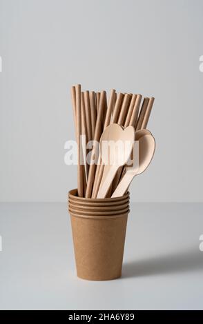 Braune Einweg-Pappbecher, Trinkhalme und Löffel auf weißem Hintergrund. Zero-Waste-Konzept. Stockfoto