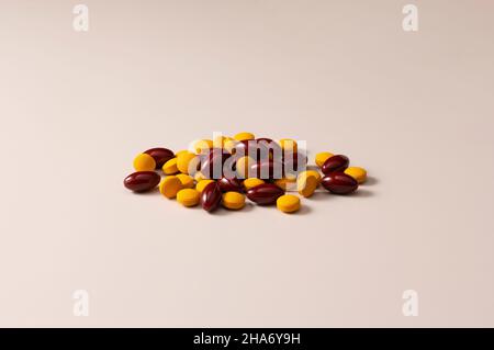 Braune und gelbe Pillen auf beigem Hintergrund. Konzept von Arzneimitteln und Nahrungsergänzungsmitteln. Stockfoto