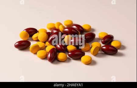 Braune und gelbe Pillen auf beigem Hintergrund. Konzept von Arzneimitteln und Nahrungsergänzungsmitteln. Stockfoto