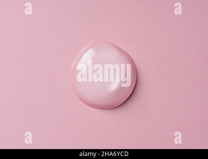 Transparenter Geltropfen auf rosa Hintergrund. Flüssige Geltextur. Beauty-Serumtropfen. Transparente Hautpflegeproduktprobe. Stockfoto